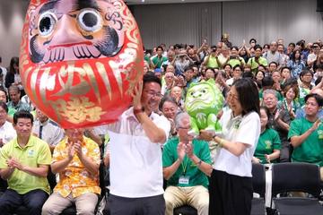 Genta Koja raises a victory daruma as supporters applaud on Sunday night after his win in the Okinawa gubernatorial election