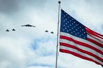 A B-2 bomber and its fighter escorts pass over the flag during the arrival ceremony for President Xi's state visit to the White House